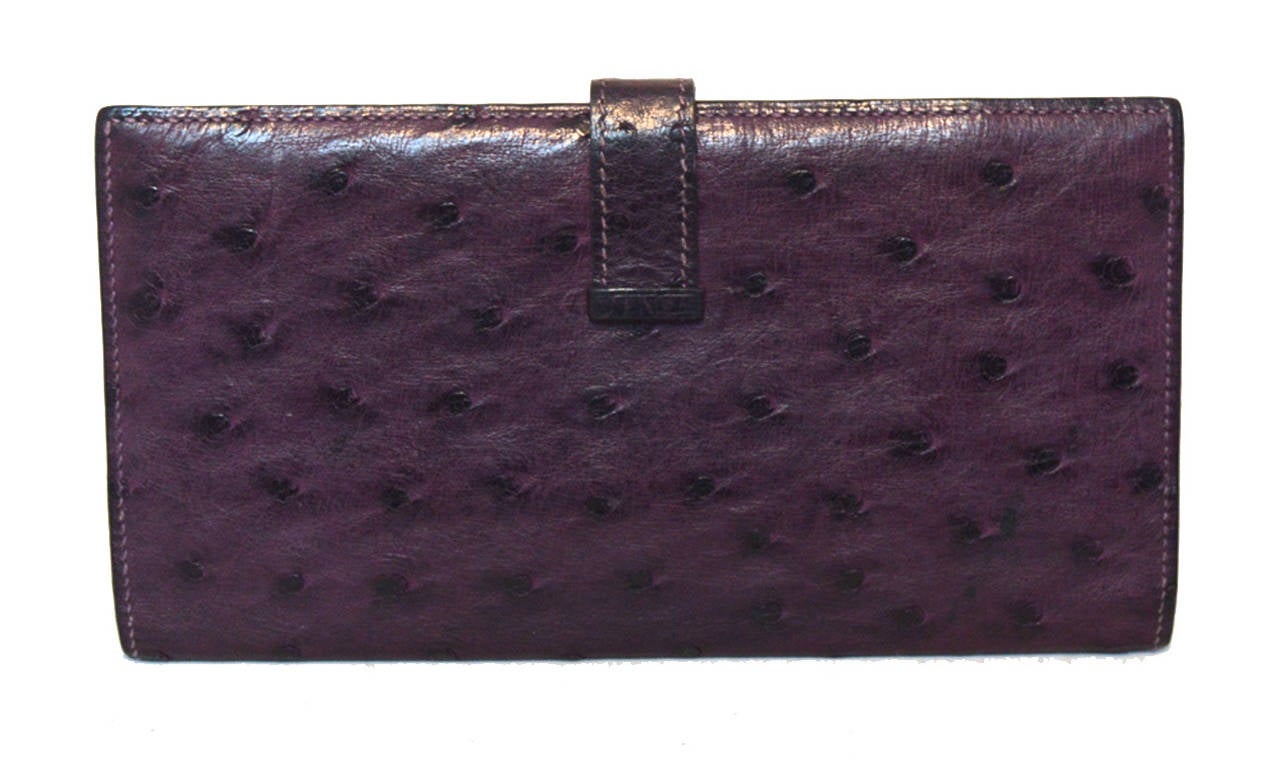 RARE HERMES purple ostrich leather wallet in excellent condition.  Deep purple ostrich leather exterior trimmed with silver H strap closure along front side.  Strap opens to a purple leather interior that holds 5 credit card slit pockets. 2 slit