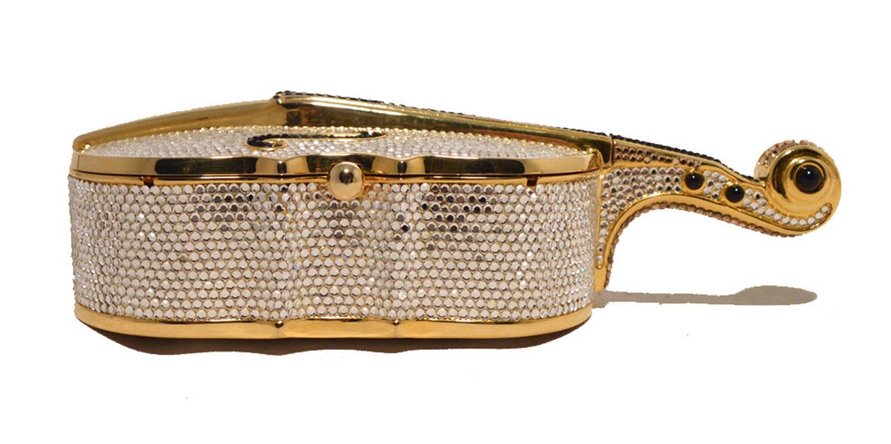 RARE Judith Leiber swarovski crystal cello minaudiere in excellent condition.  Gold Cello shaped exterior trimmed with clear and black crystals.  Side button closure opens to a gold leather lined interior that holds 1 side slit pocket and an