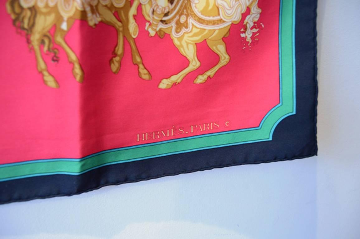GORGEOUS VINTAGE HERMES silk carrousel scarf in very good condition.  Original silk screen Carrousel design c1985 by Christiane Vauzelles features various carrousel horses over a bright red background surrounded by a navy blue and teal border.  No