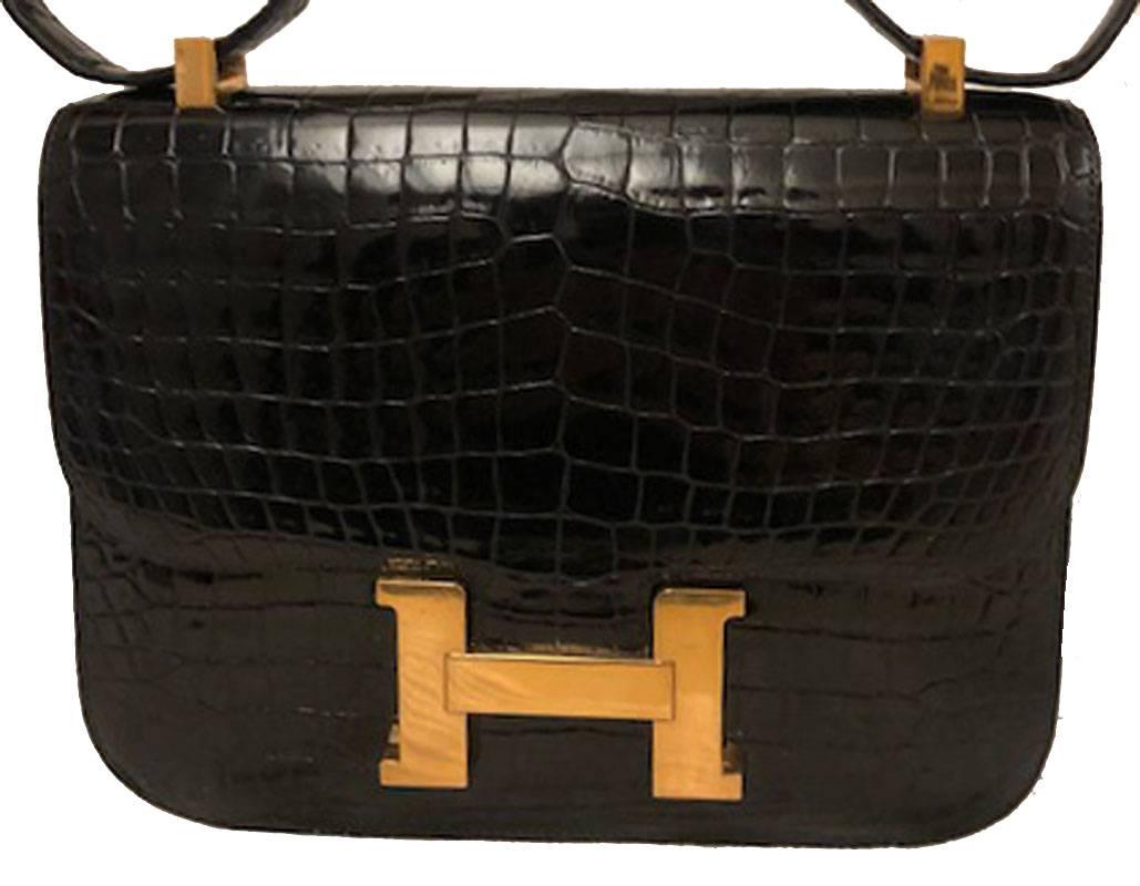 AUTHENTIC HERMES black crocodile constance bag in excellent vintage condition. Black crocodile leather exterior trimmed with shining gold hardware. Lift latch single flap style closure opens to a black leather lined interior that holds 2 slit and 1