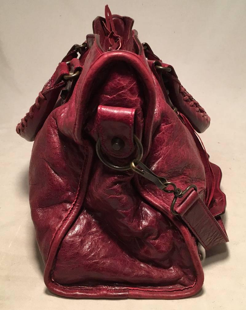 Balenciaga Red Leather Classic City Bag in excellent condition.  Red leather exterior trimmed with delicate leather fringe strips, Bronze studded hardware, removable shoulder strap, and front zippered side pocket.  Top double zipper closure opens to