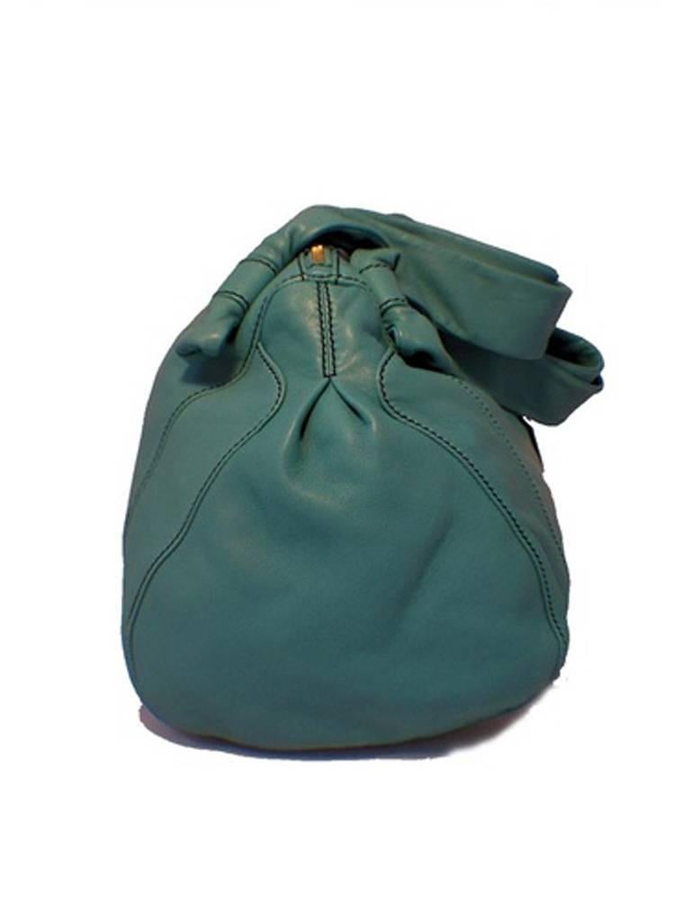 This gorgeous Valentino shoulder bag is a must have for every fashionable wardrobe.  The exterior is in mint condition featuring plush teal lambskin leather with a gorgeous rose ruffle embellishment, durable double leather shoulder straps, and
