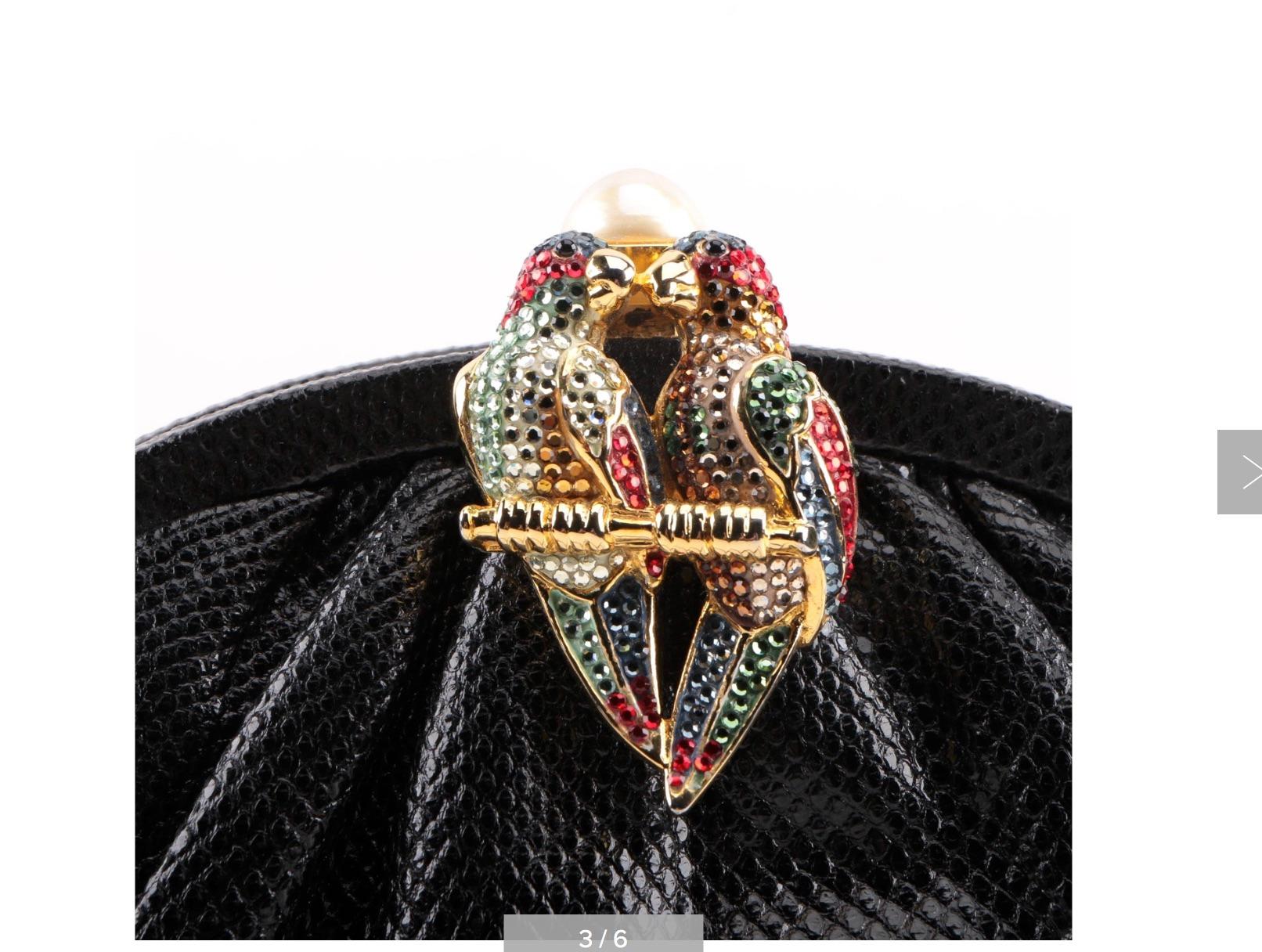 A Judith Leiber New York Elegant black karung skin Clutch Handbag. The bag has a clasp designed with two kissing parrots embellished with handset colorful Swarovski crystals and a large pearl on the gold clasp.
The purse opens to a satin lining with