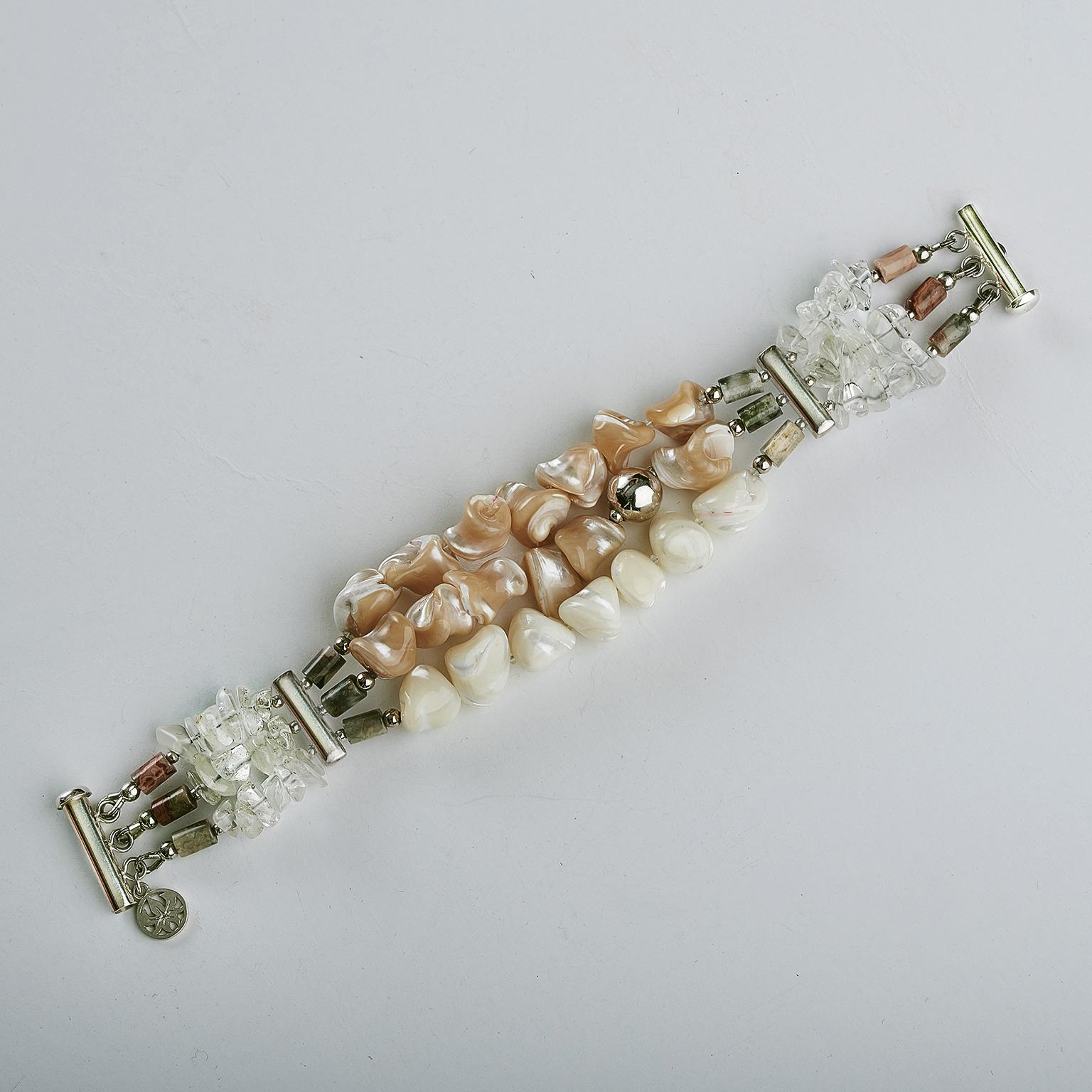 The three strand bracelet composed of naturally colored, with off-white and caramel ( MOP ) mother of pearls nugget shape trochus, 18-10 mm beads and free-form crystals that contrast beautifully with the multicolored jasper tubes, accented