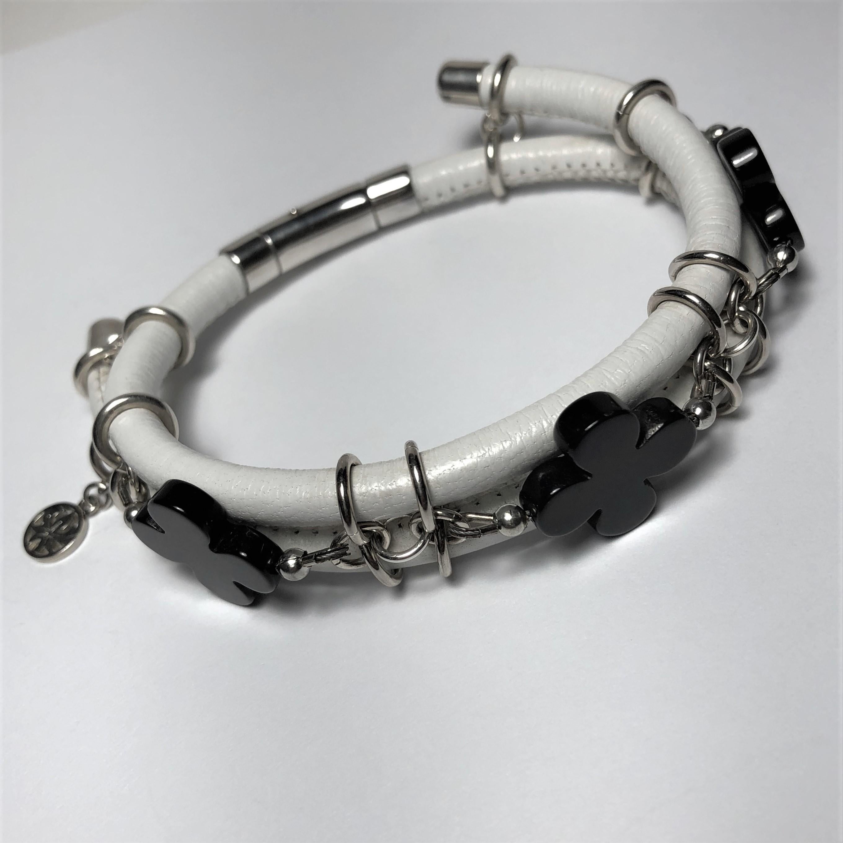 The white stitched leather double bangle bracelet made with three black agate clovers cut gemstones and connecting by silver links and a barrel lock. 

Length: 8.0 in ( 21.0 cm )

Black agate clover cut 0.7 x 0.7 in ( 17.0 x 17.0 mm )   
White