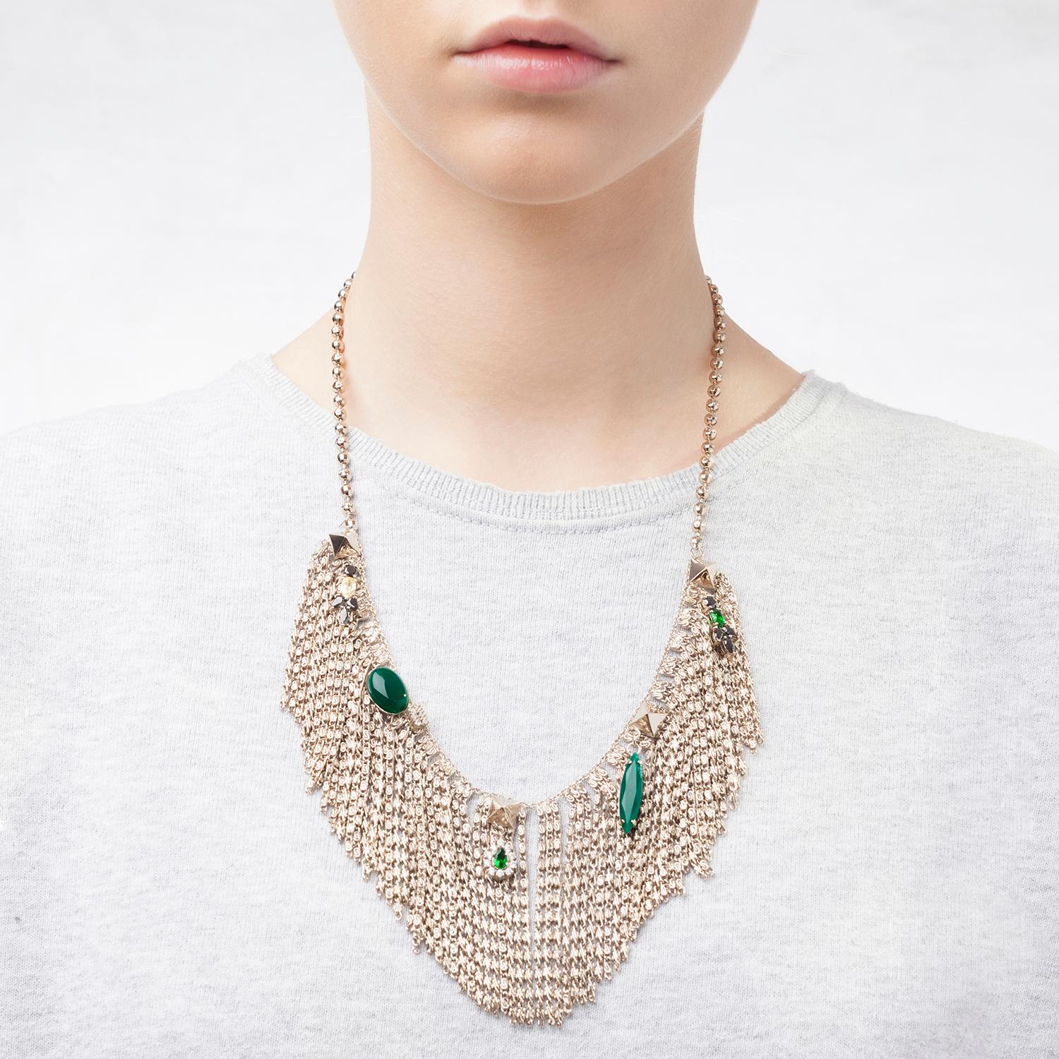 This unique necklace is designed to blend a harmonious balance between elegance and extra impact. The necklace features a central strand of fringes enriched by trinkets, vintage jewelry details, green agate navettes and cabochons. Beautifully dotted