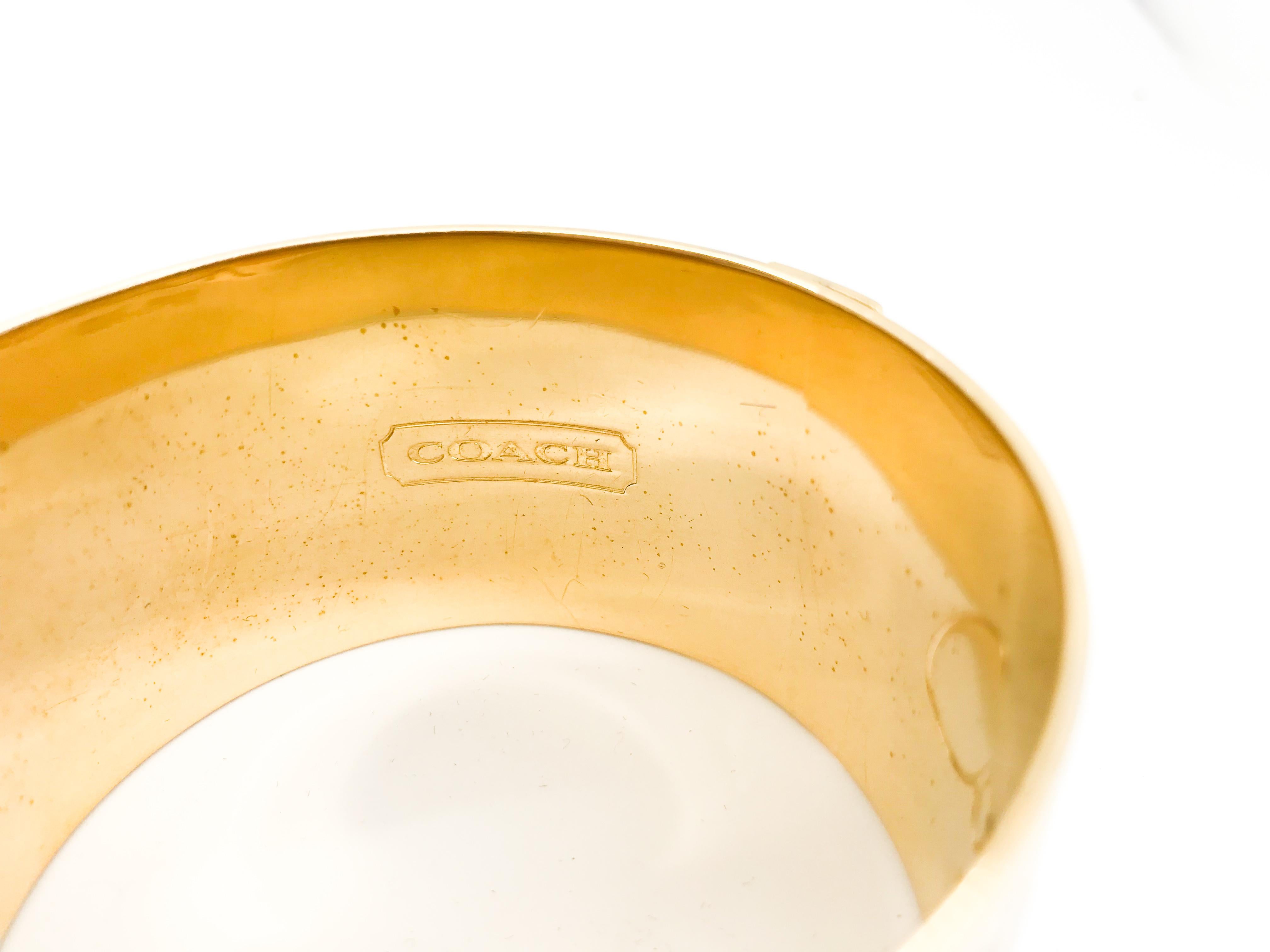 Coach Enamel Gold Tone Bangle Bracelet.  Marked Coach est 1941

circumference - 8 inches 
1.5 inches wide

Material: Gold Tone Stainless Steel , Enamel or Lacquer