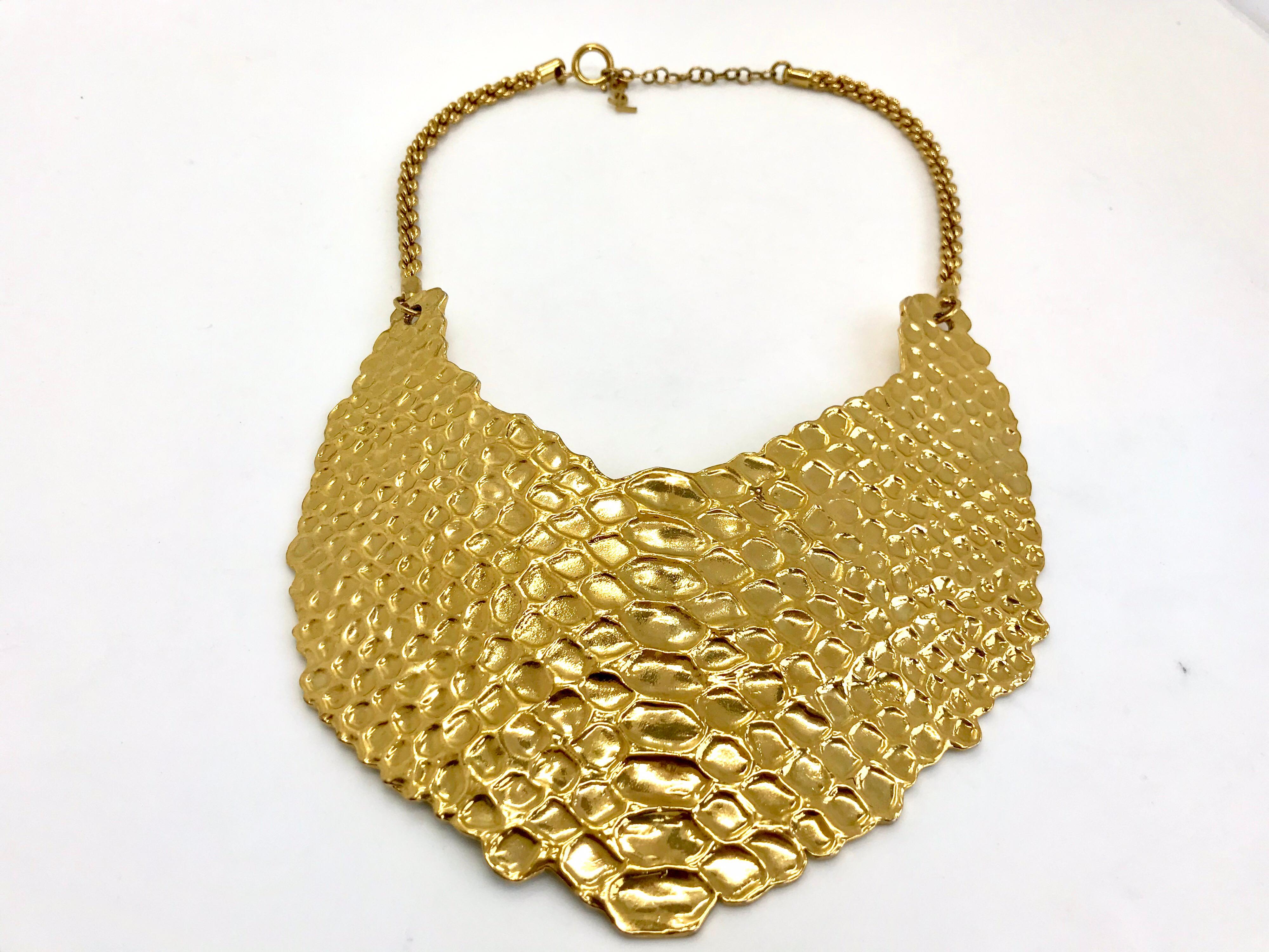 YSL Vintage Snakeskin Effect Statement Bib Necklace.  Stunning carved reptile skin design on an antiqued gold-tone setting.

Signed YSL on hangtag from lobster clasp.

A real show stopping piece!

Measurements:
width - 5.5 inches
length 3.5