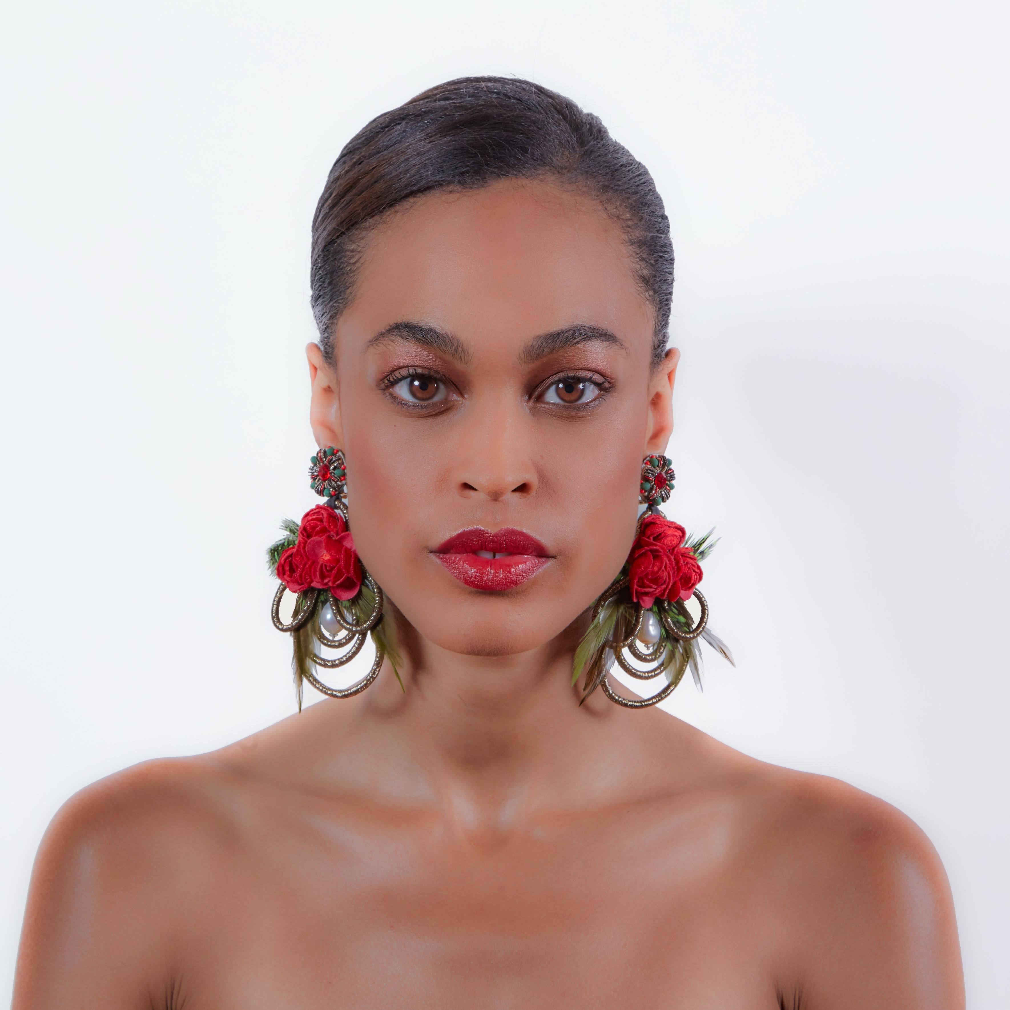Make a festive statement in the Mangueira earring. Mother-of-Pearl, peacock feathers, and stunning red florals create a liveliness that spices up any wardrobe. 