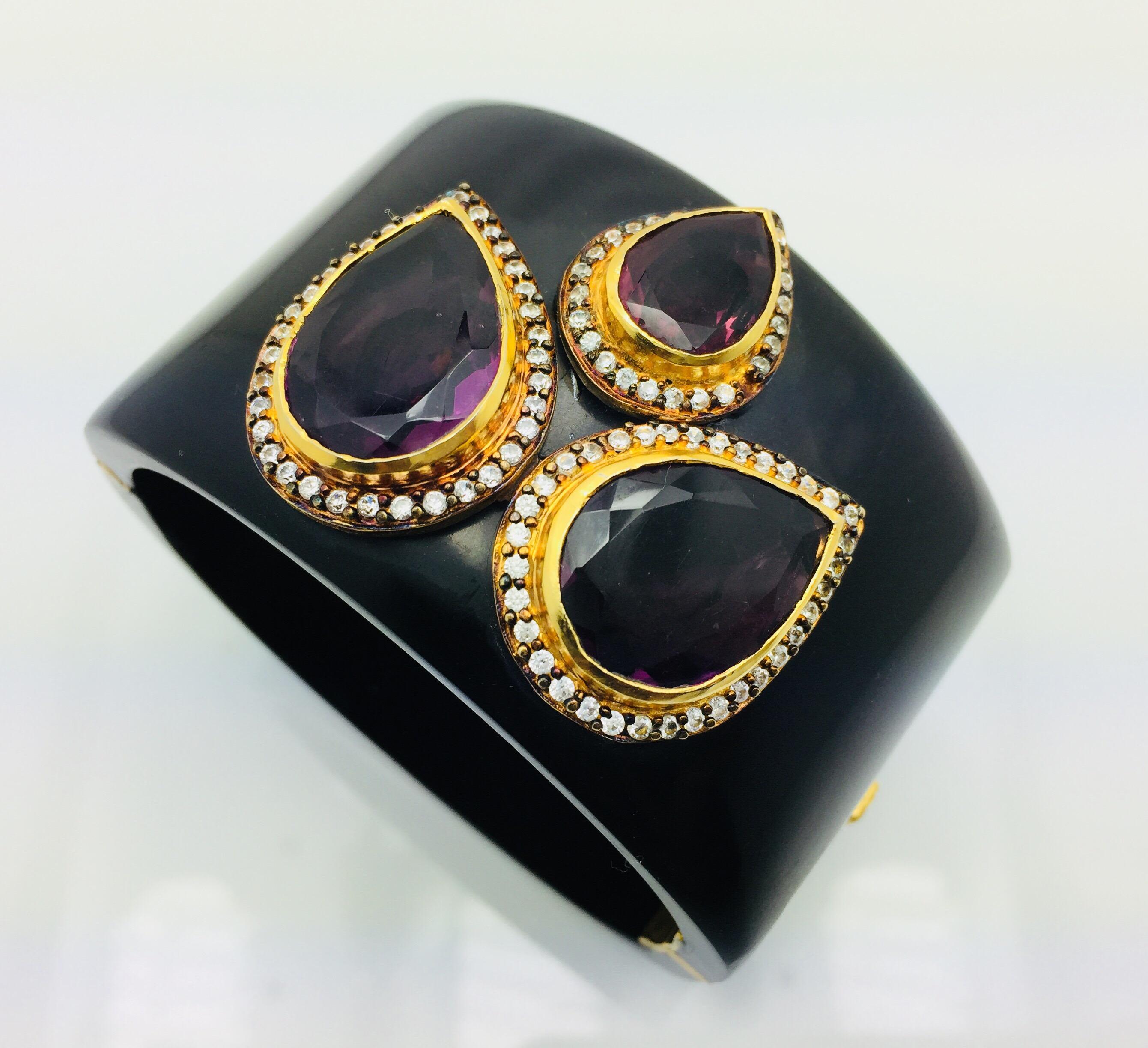 Florence Resin Cuff is handcrafted with three pear shaped faux amethyst stone.  The bold piece is surrounded by  cubic zircons on each motif. The bracelet is hinged and fastens with a push tab insert closure.  Limited Edition - Only 1 available.  A