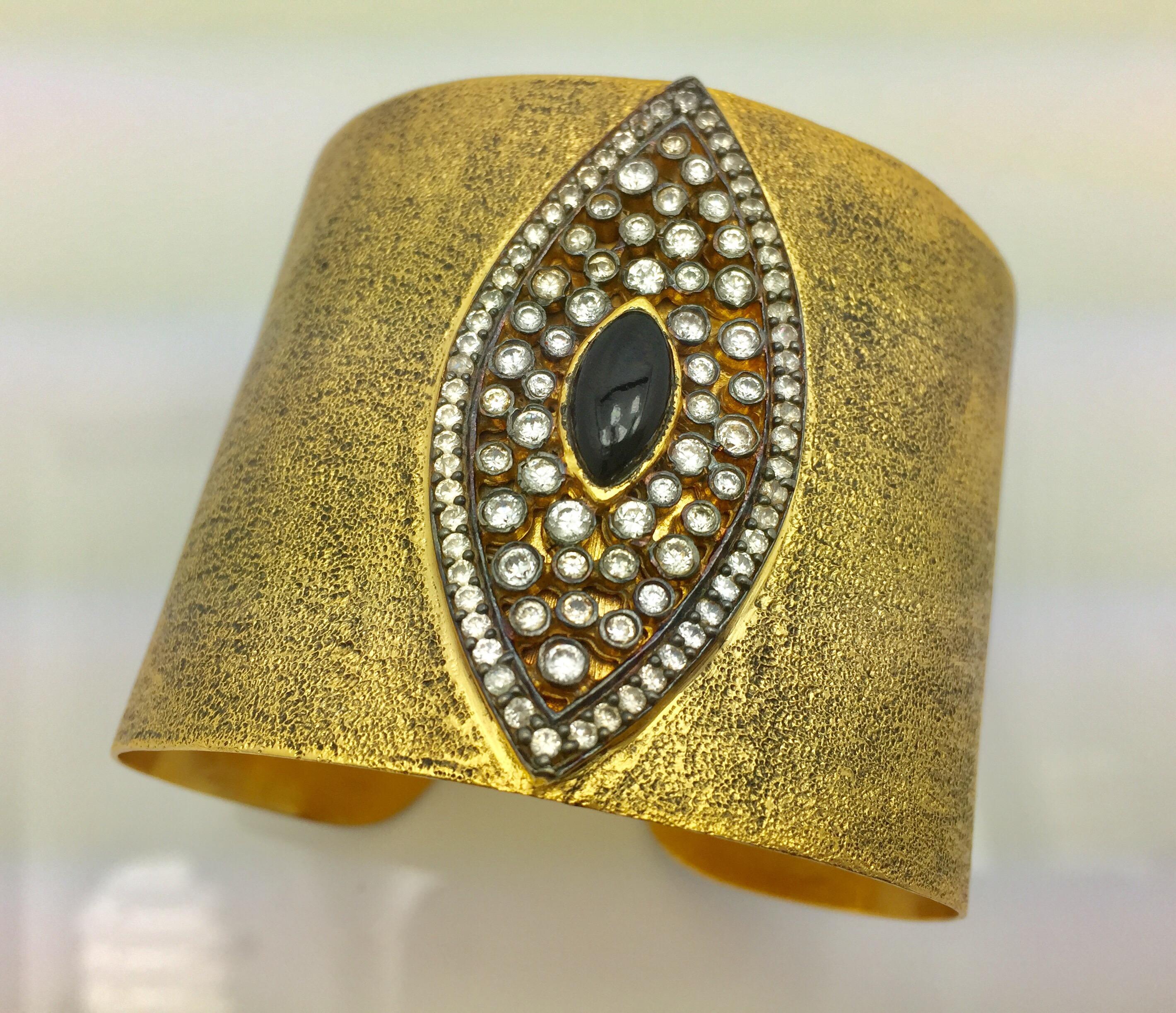 The evil eye, thought to provide protection from evil spirits is beautifully captured in this gold, black and CZ hand brushed cuff. 
The statement cuff is lavishly adorned with sparkling CZ stones.  Cuff is adjustable.

Measures approximately 2