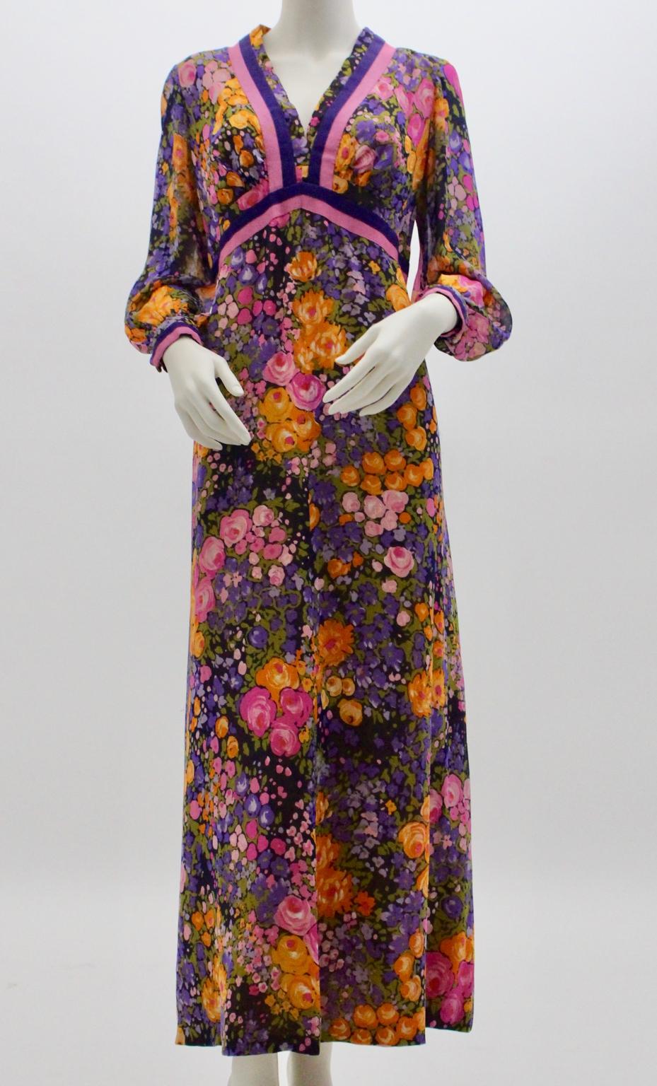 Charming vintage maxi dress with multicolored flower print in pink, lilac, lavender and orange and a dark underground from the 1970s from the designer Herbert Schill.
The little transparent long sleeves features a cuff with two buttons, furthermore