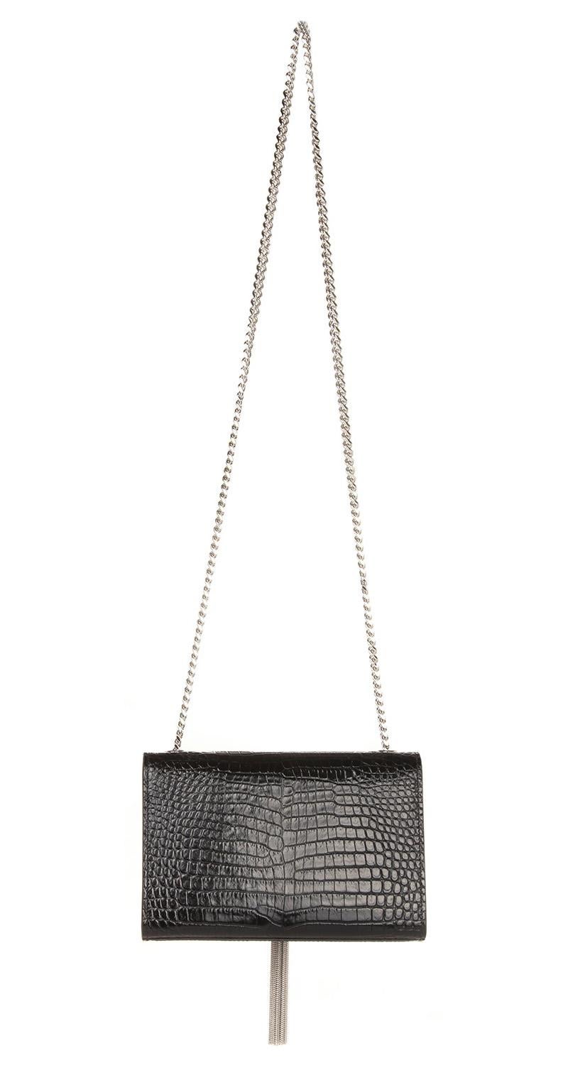 Monogram small Kate bag with metallic tassel in crocodile embossed shiny leather. The bag features a gold chain link shoulder strap and a full facing flap with the classic YSL Monogram and magnetic snap closure. Bag can be carried as shoulder or