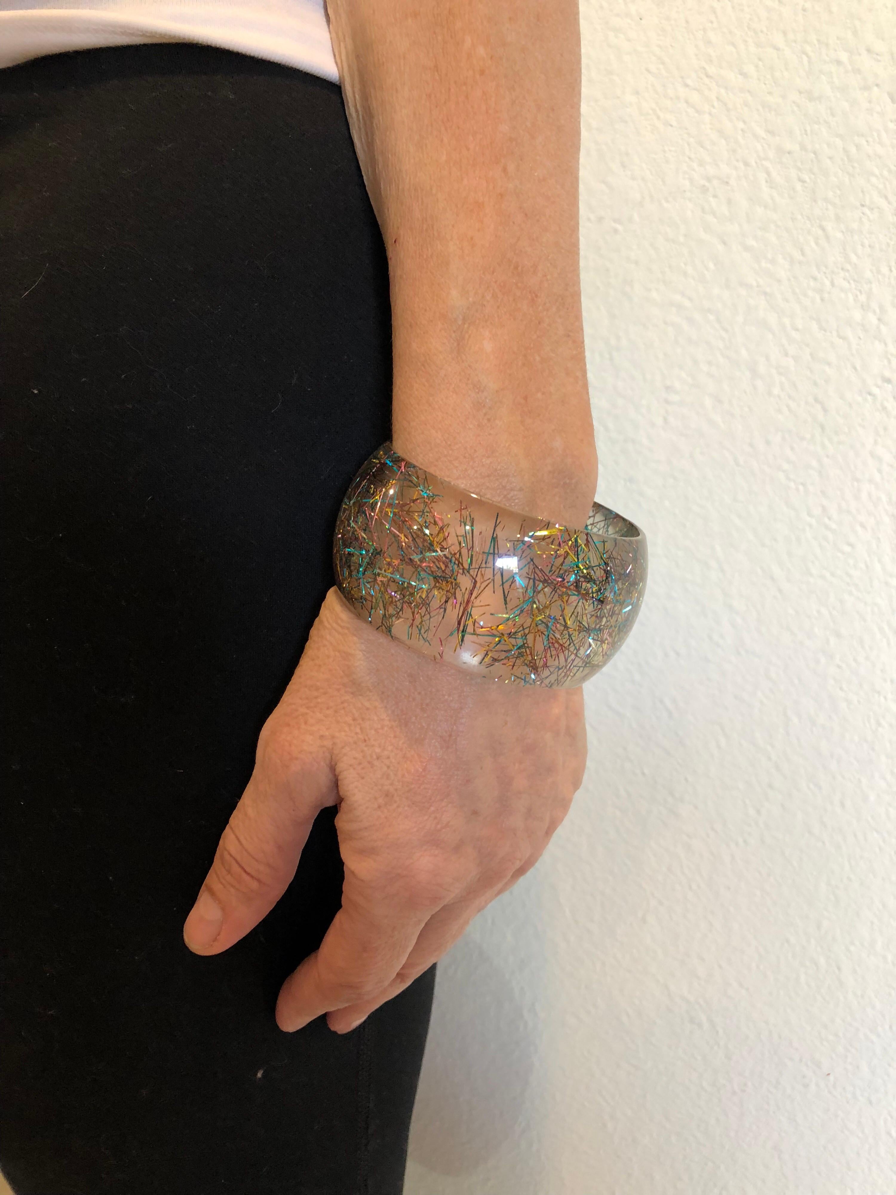 Vintage French lucite bangle c.1970's - the bangle is comprised of clear lucite which is injected with colorful metallic confetti in pink, blue and yellow. The statement bracelet is in excellent condition and measures 2 6/8