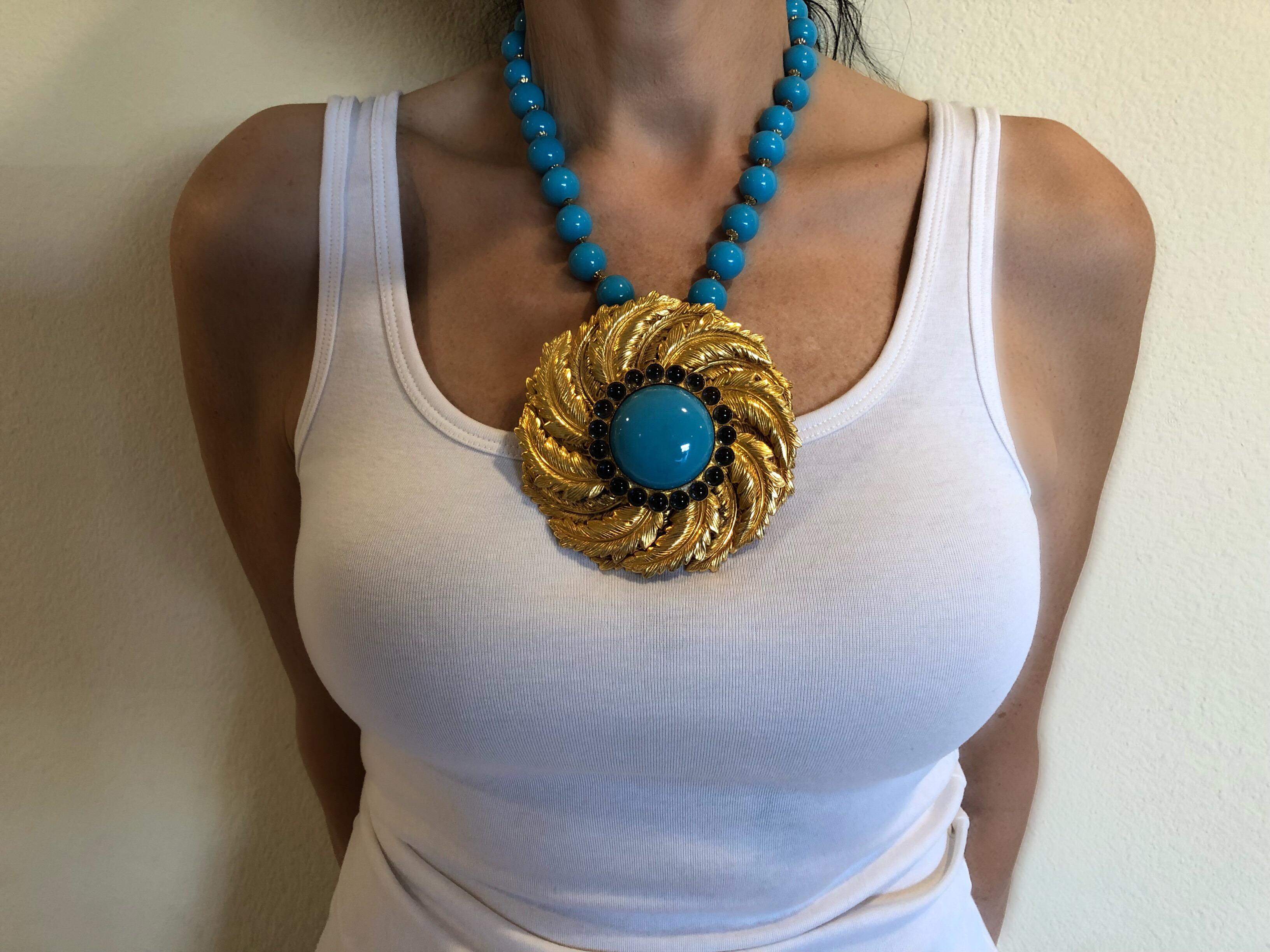 A unique (one of a kind) statement necklace by William de Lillo. The prototype necklace is comprised of a chunky faux turquoise (robin's egg blue) glass necklace with gold-tone detail - adorning the necklace is a large architectural circular pendant