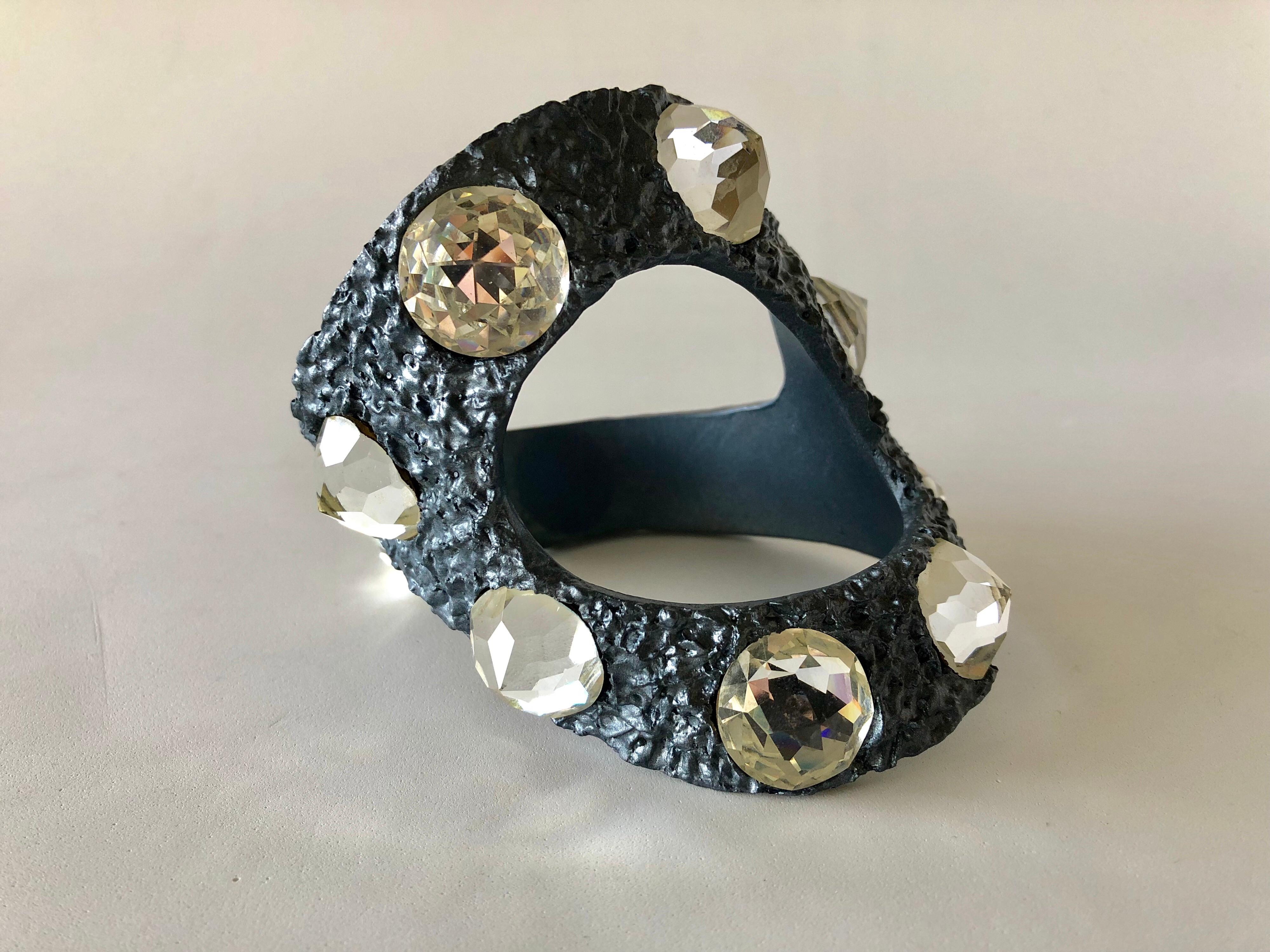 This wearable piece of mid-century modern art was created by a New York underground artist Betty Milham in 1965. The abstract statement bracelet is comprised out of paper-mache and resin and finished with a patinaed gray lacquer, which is accented