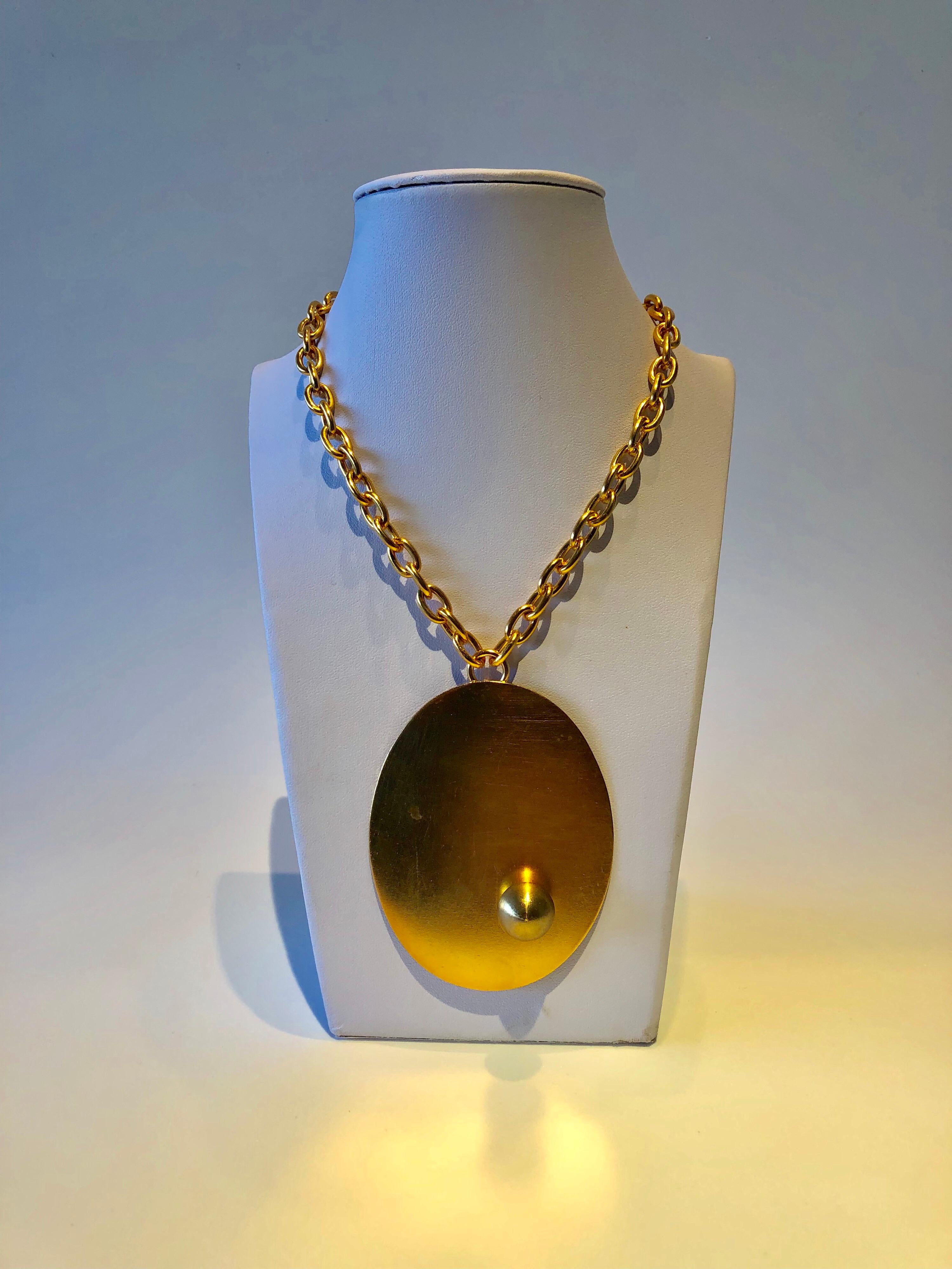 Vintage modernist pendant statement necklace comprised of mat gold-tone metal - the necklace features a minimalist modern design throughout, accented by a large oval pendant. Made in France in the 1970s by Premiere Etage - an accessories atelier