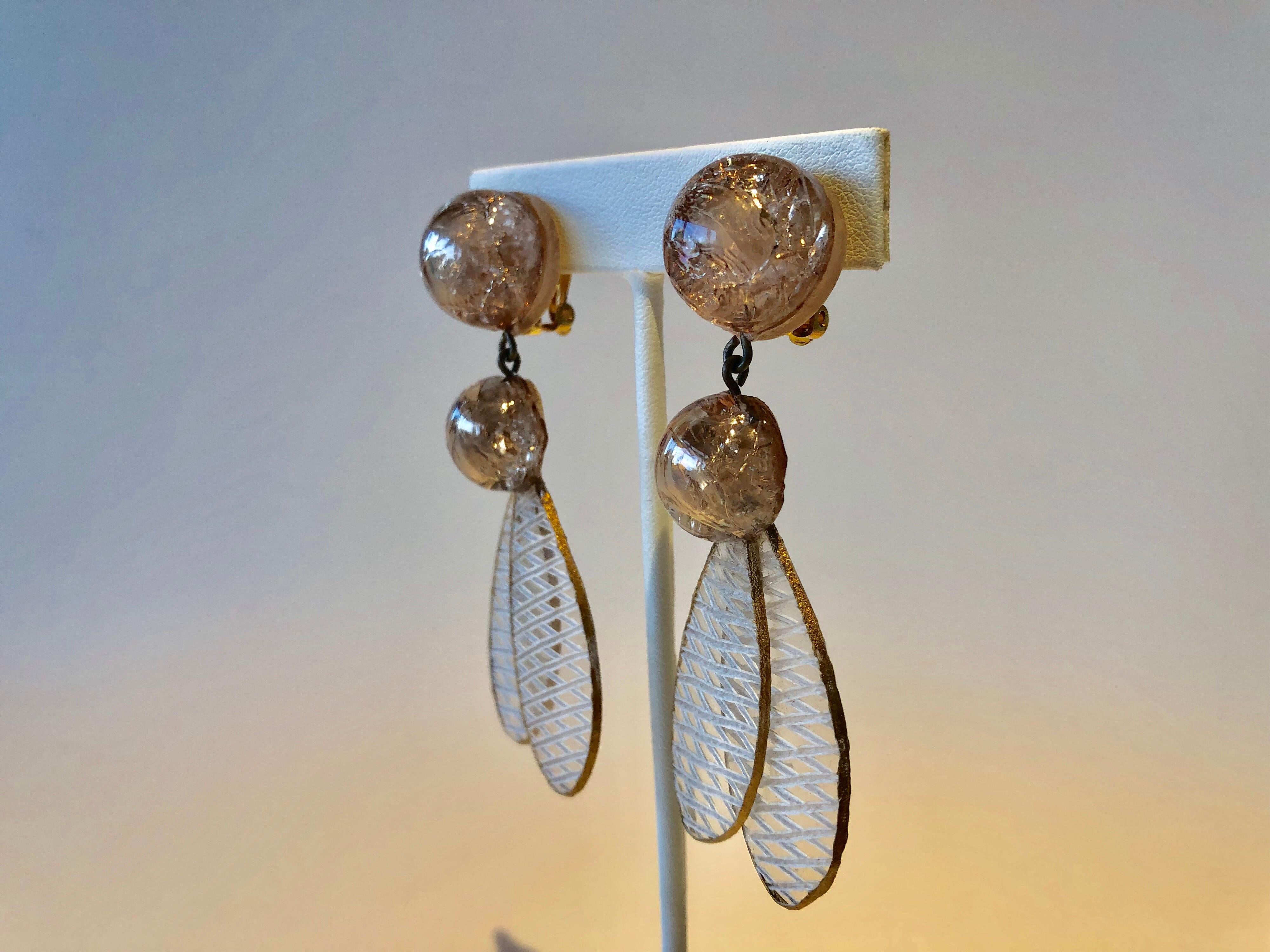 Light and easy to wear, this handmade pair of artisanal earrings was made in Paris by Cilea. The earrings are comprised of champagne color enameline (resin and enamel composite) and depict dragonfly wings. Throughout the clip-on earrings you can see