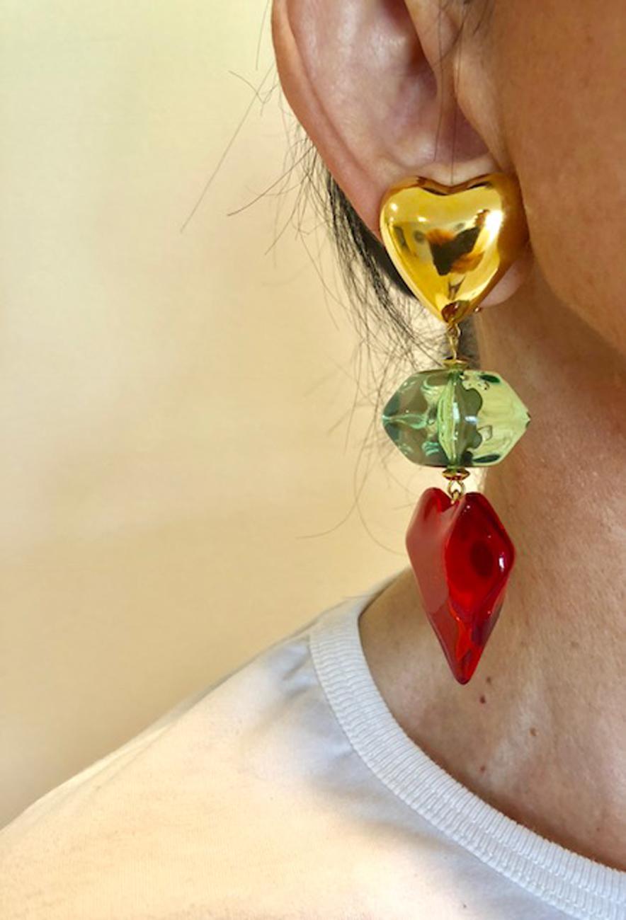 These geometric oversized lucite dangling chandelier clip-on earrings were handcrafted in Paris. The earrings feature three distinct segments of colored lucite, a faceted lime green disk, and a large translucent red heart, which is accented by a