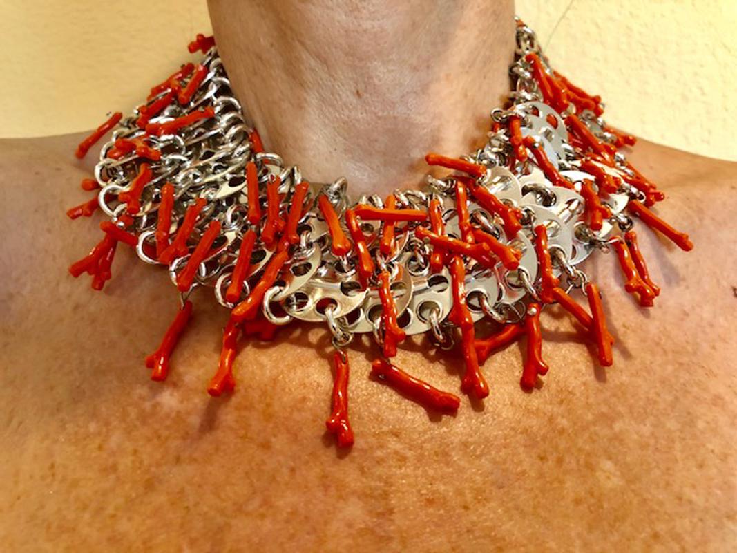 This exceptional and modern vintage necklace is comprised of perforated silvertone disk findings, which are all joined together to lay on your neck comfortably. The necklace is accented by suspended coral branches which add drama and movement.