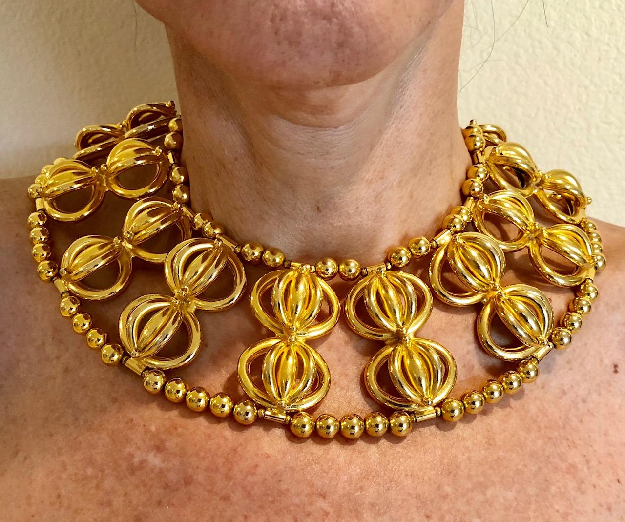 Chic and fashion current sculptural statement bib necklace by William de Lillo. The monumental necklace is comprised out of gold-tone metal beads which are adorned by architectural domes, the necklaces wow factor comes from the combination of all