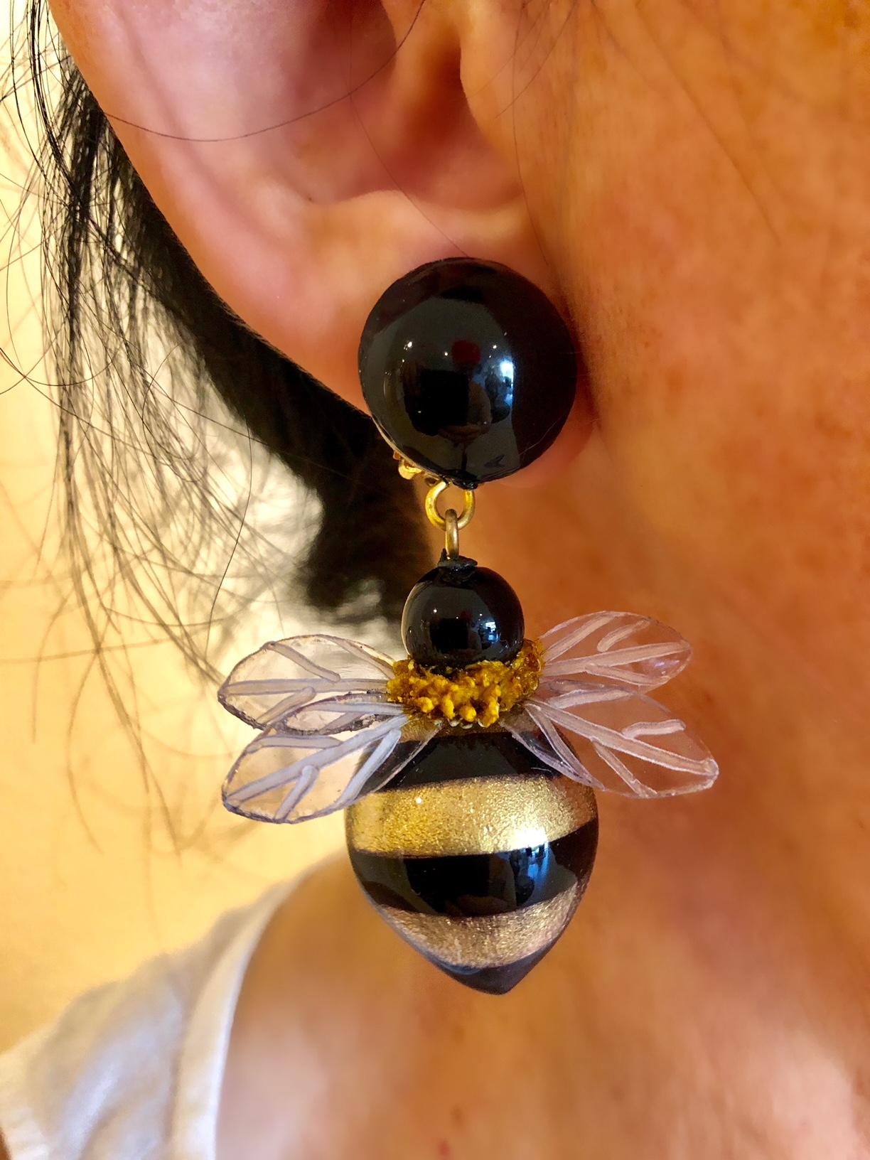 Light and easy to wear, these handmade fashion forward artisanal drop clip-on earrings were made in Paris by Cilea. The earrings feature two whimsical enameline (enamel and resin composite)  black and gold Bumblebees with detailed lucite wings.

