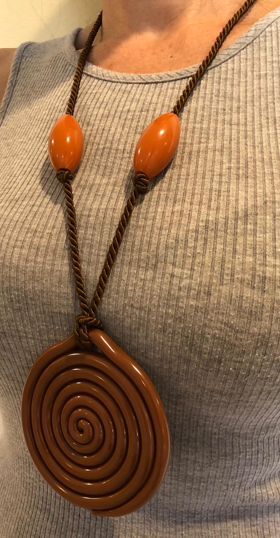 Simple and bold  mid centuryFrench silk-cord statement necklace featuring large brown oval Galalith beads and a huge center swirl pendant. The swirl pendant measures 3.75 inches x 3.50 inches, made in France c.1960's.