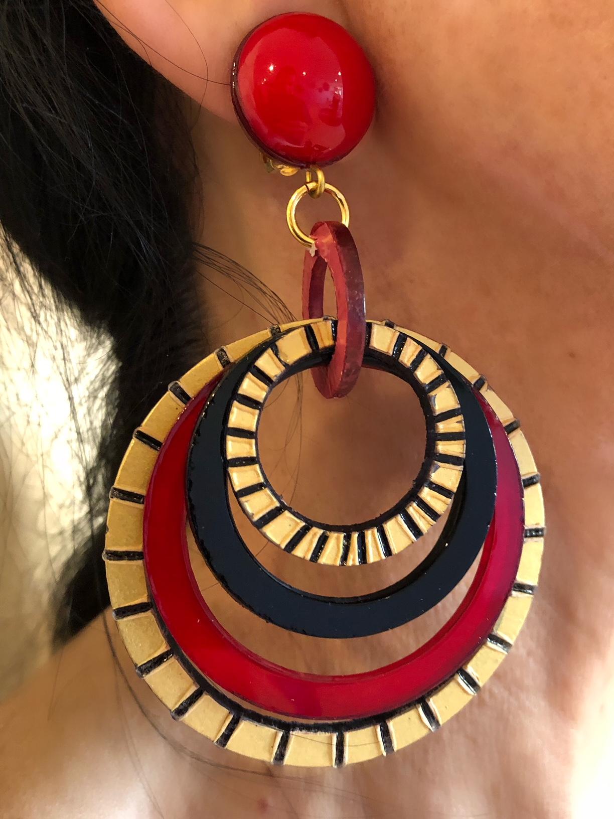 Light and easy to wear, these handmade artisanal hoop clip-on earrings were made in Paris by Cilea. The earrings are comprised of black, red and gold enameline (resin and enamel composite) and depict three-dimensional pop art circles. Throughout the