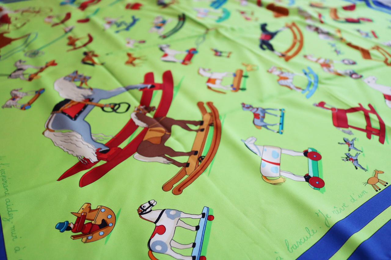Hermes Raconte-moi le Cheval Blue and Neon Green Toy print Scarf 
This Hermes silk scarf was designed by Dimitri Rybaltchenko.

-Lime green, blue and multi color printed children's rocking horses. 
-French words of children are inscribed around the