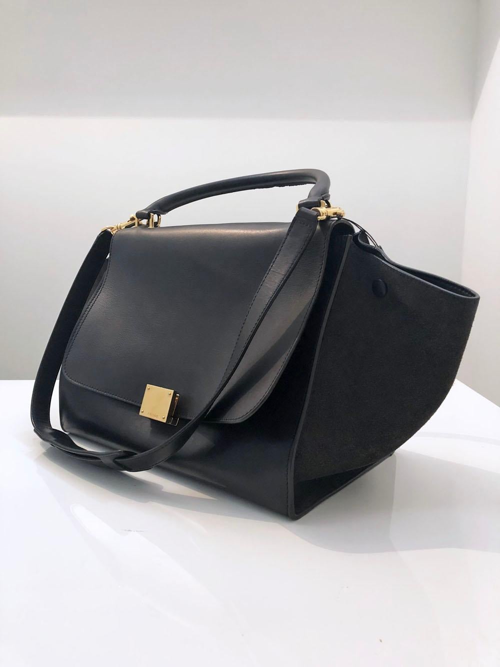 The Celine Trapeze bag will never go out of style. An essential for carrying all your everyday necessities with a removable, adjustable cross body strap and top handle with gold hardware. One zip pocket on the back. The tip flap opens to reveal a