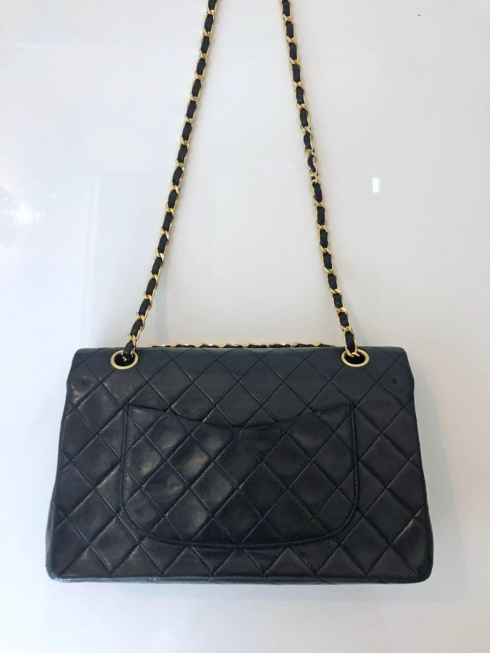 Vintage Chanel black quilted lambskin double flap bag with burgundy lambskin lining and gold hardware. One back slip pocket, one zip pocket under the top flap with a second inside flap covering the inside compartment and one inside slip pocket.