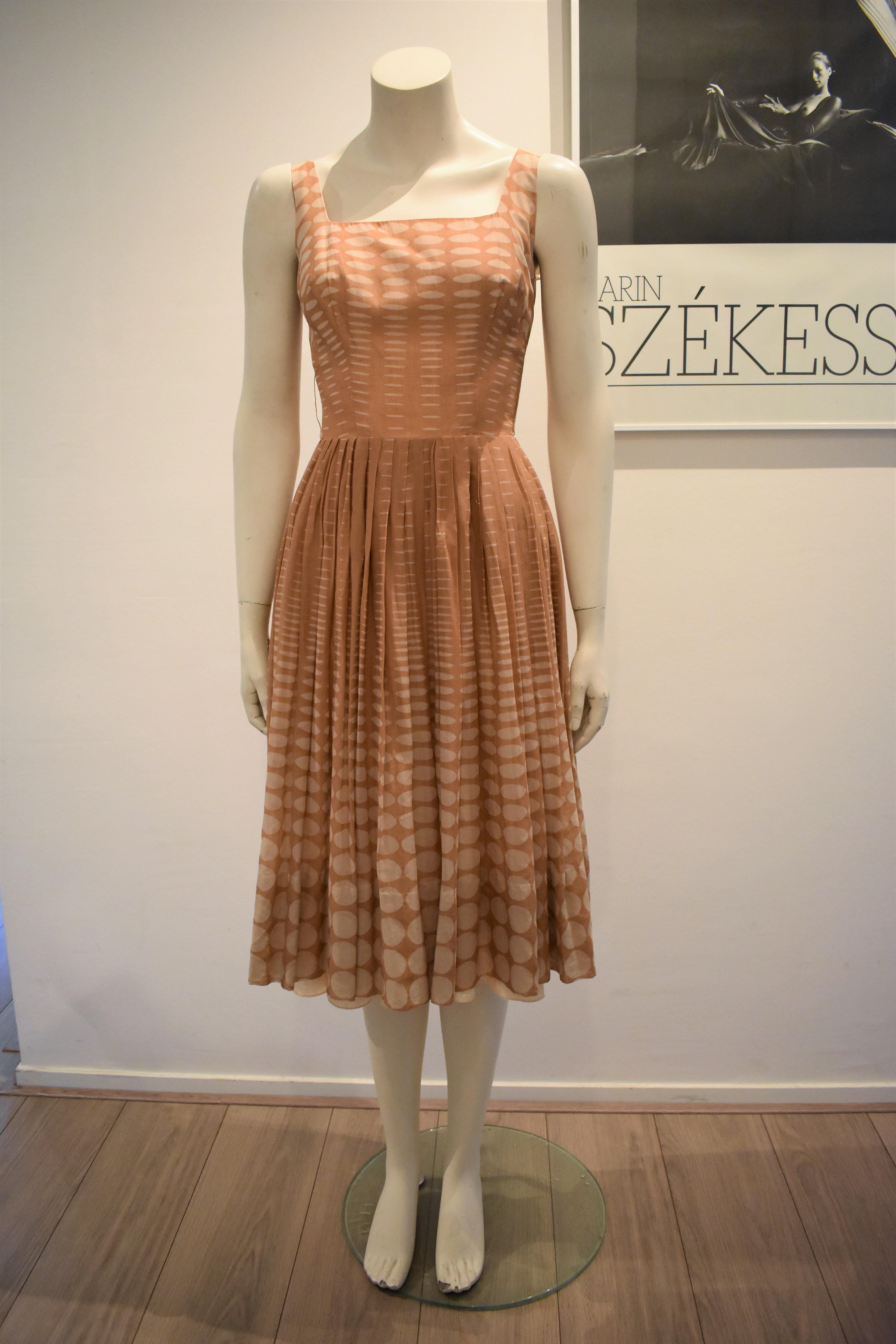 This lovely dress is made from batiste (a lightweight, semi-sheer cotton fabric) and it has a salmon slip dress underneath. The dress has a very tiny waist (the zipper could not completely close on the mannequin). The dress has 2 very thin belt