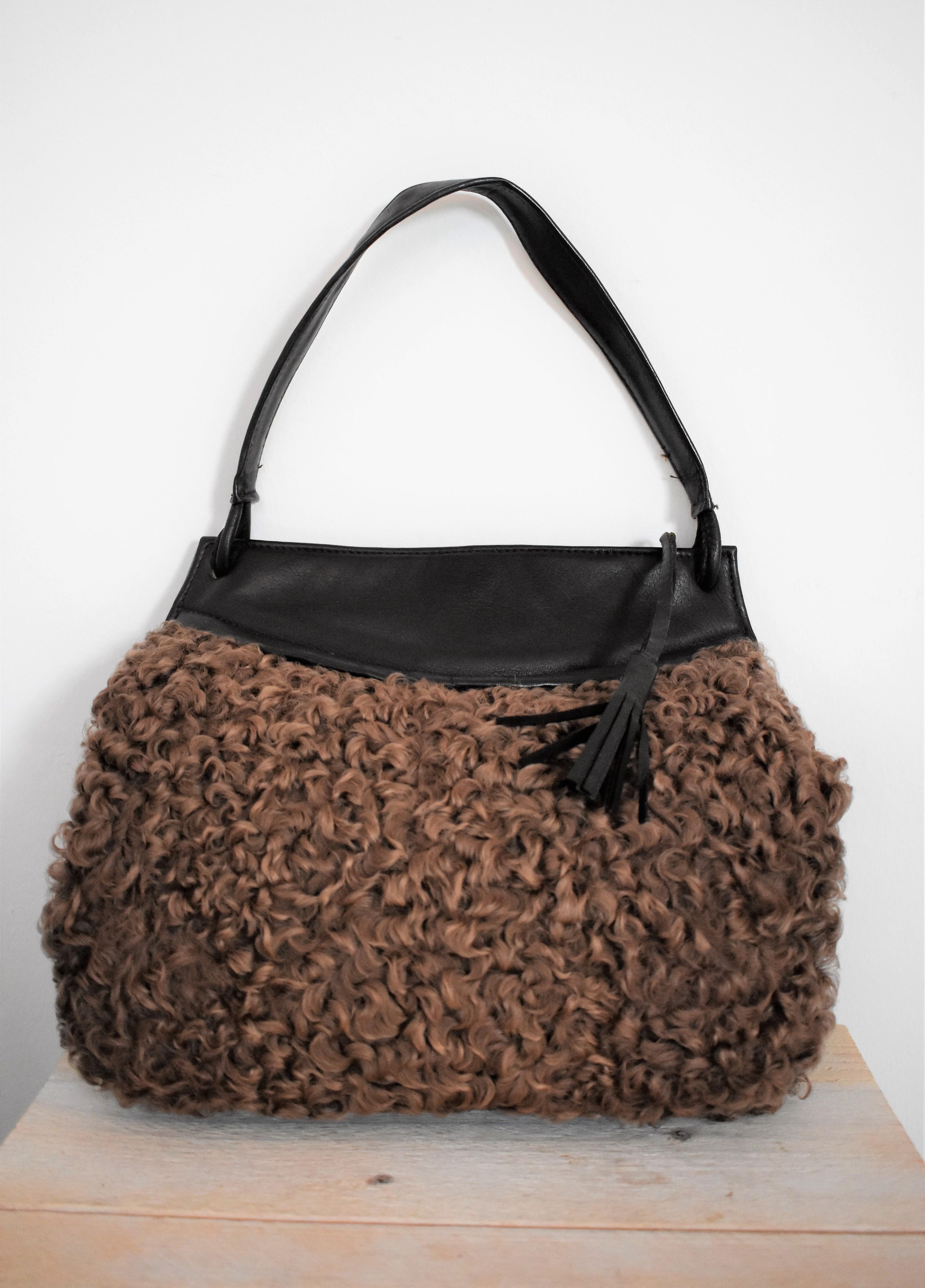 This handbag is made from very soft curly lamb fur and leather. It has a hole inside, lined with soft fabric, which can be used to keep your hands warm. it was made in crica 1950 and it is in very good condition. 