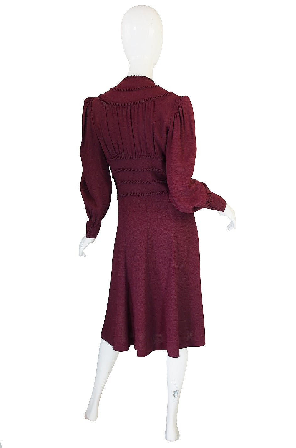 What a glorious 1940s swing dress! These are getting harder and harder to find and to find a jewel like this one is just wonderful to have. The fabric is a deep burgundy moss crepe that drapes wonderfully when on. The bodice is cut to have a