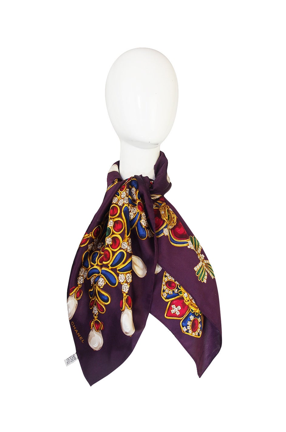 Beautiful silk Chanel scarf on a bright combination of purples and brilliant jewel tones with a jewellery print that covers the scarf. The colors are bright and vibrant and it is quintessentially Chanel.

Appears to have been never been used or