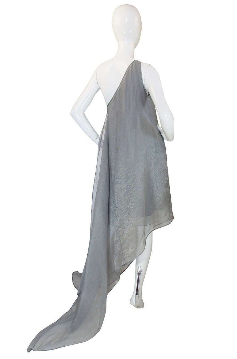 Donna Karan can really knock it out of the park sometimes and this one is a home run. The fabric is a silver toned silk organza that floats over a shorter sexy inner dress whose exterior is the same fabric. This gives it dimension and depth and