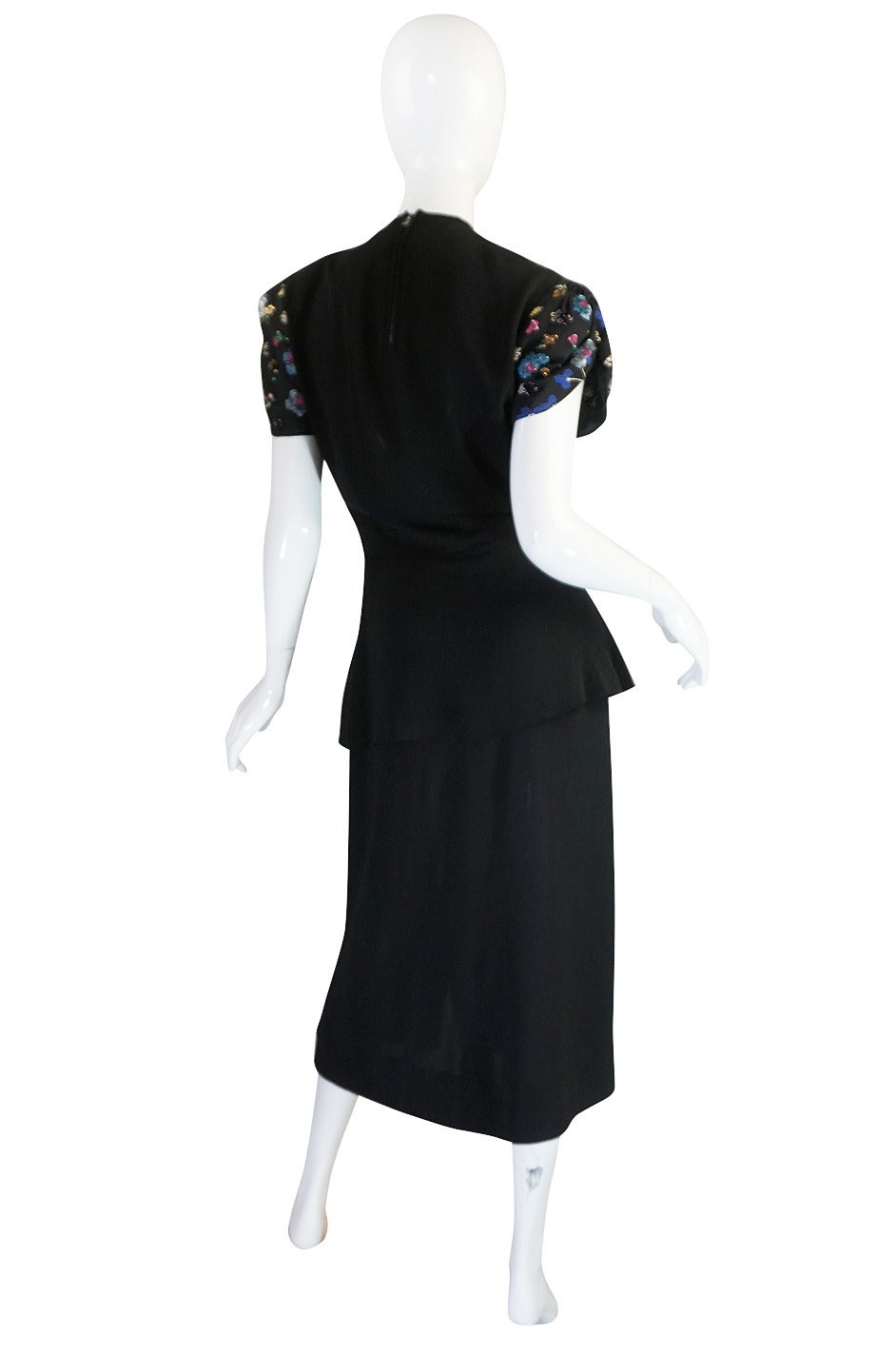 This is an exquisite late thirties, early 40s black silk crepe dress whose bodice is entirely covered with hand painted flowers that are highlighted with hand applied sequins. It is one of the most spectacular dresses from this period I have had in