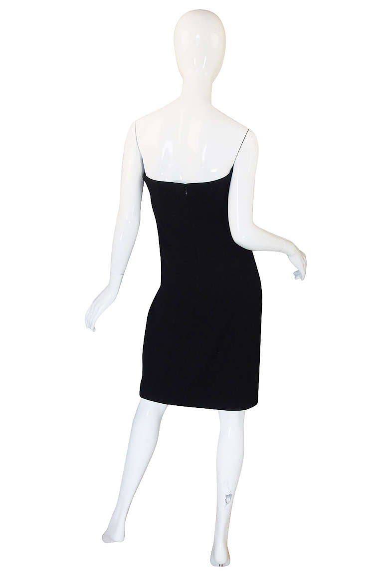 I love the graphic feel of this little black strapless dress from Geoffrey Beene with its two saucy cream felt details on the bust. The body is a slim column of black silk wool crepe and the fabric has a slight bit of texture to it so as you get