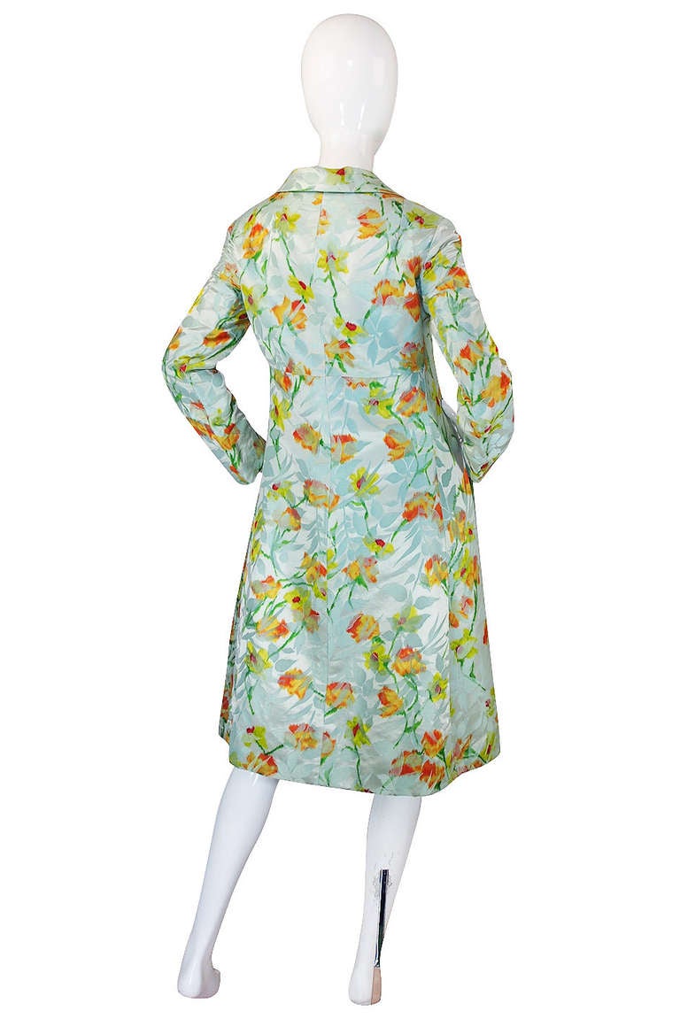 What a beautiful coat! The fabric is just wonderful - it is a silk brocade down in a pale combination of greens with little pops of yellows and corals done to create a beautiful floral pattern. Because different weaves have been use through the silk