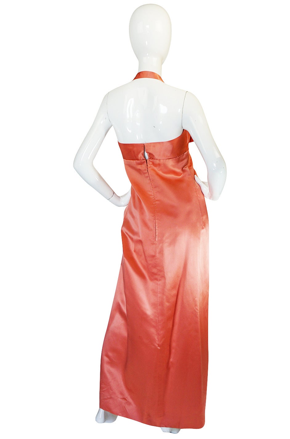 This is a wonderful gown from the late 1950s, maybe early 1960s. The gown is extraordinary. A heavy grade silk satin is hand dyed a salmon pink and that color, combined with the fabric choice, makes it seem to have an inner glow. A simple sheath