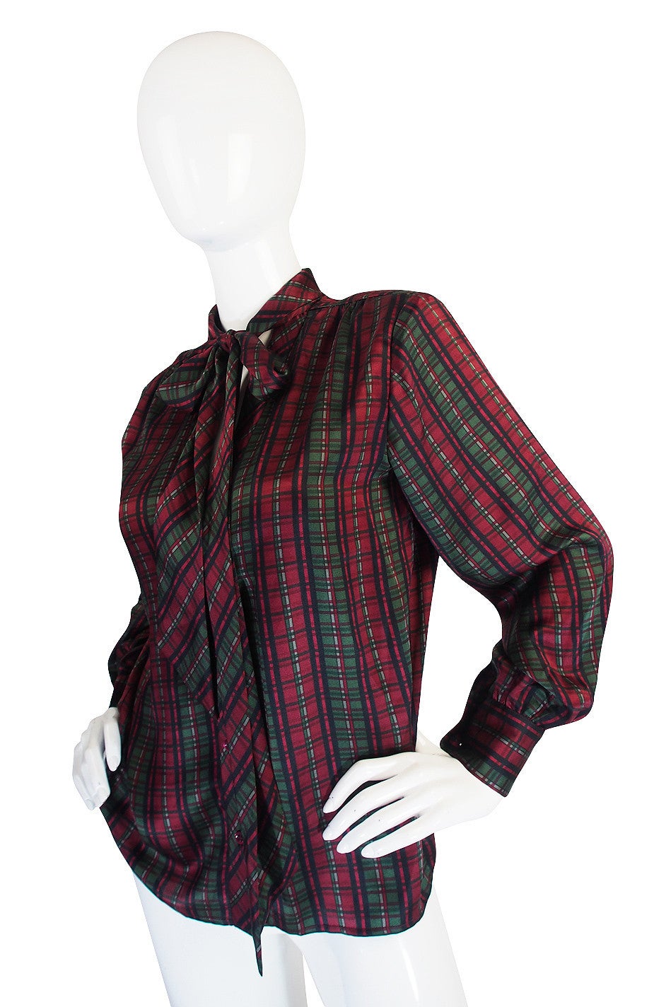 This beautiful silk blouse is a classic from Yves Saint Laurent. It is an amazing color and print combination - a gorgeous plaid down in deep red and greens on a fine silk. It has that signature YSL tie at the neck and it can be left unbuttoned for