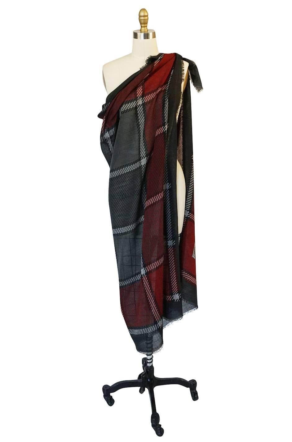

Gorgeous and absolutely huge, this Yves Saint Laurent scarf is a mix of a deep burgundy red with taupes and with pops of silvered grey to highlight the fantastic plaid design. It is made of a fine silk and wool mix that is extremely light and
