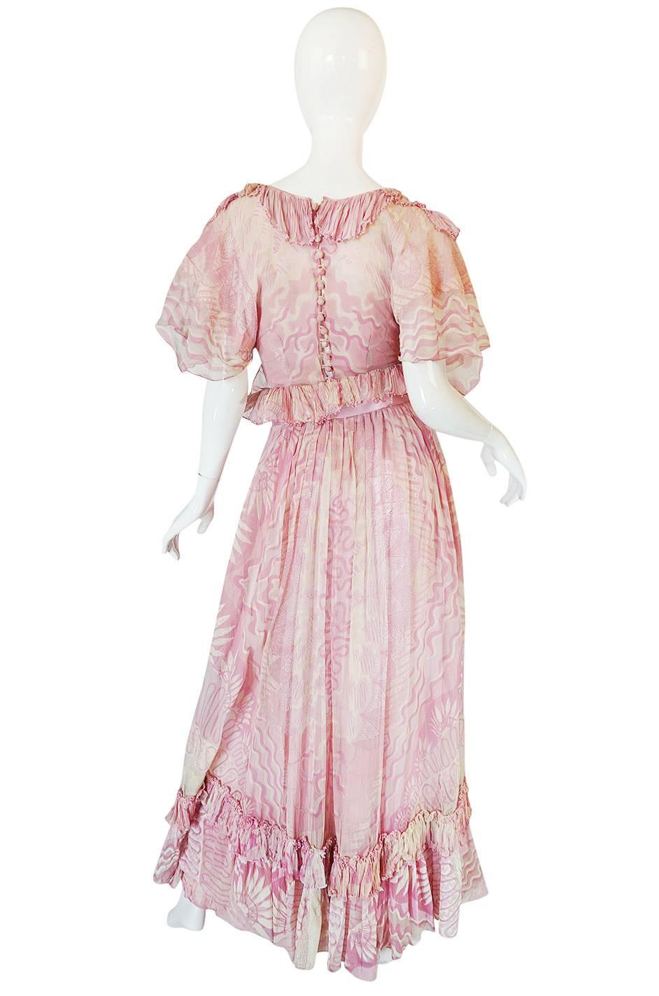 

This rare and amazing hand painted silk gown set by Zandra Rhodes in a very rare piece from one of her most coveted of all her collections - The Lily collection from 1974. It is constructed of a fine, pale pink, silk chiffon that is entirely