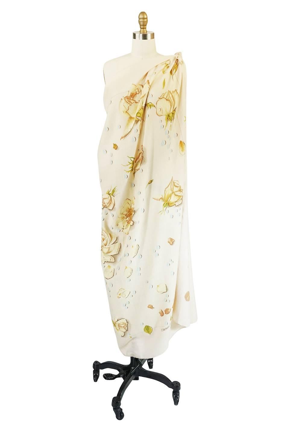 

Beautiful cashmere and silk travel shawl by Hermes that depicts a stunning and romantic  pattern of flowers, leafs and water drops on a muted cream backdrop. These are fabulous to travel with as they are light and warm but fold up quite small.