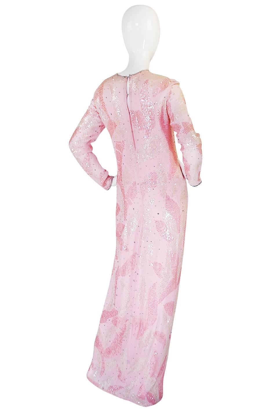 

A whisper of pale pink silk chiffon makes up the base of this beautiful dress by the great American designer, Halston. The silk is cut on the bias and then covered in pink and iridescent cream sequins so the entire dress shimmers in the lights