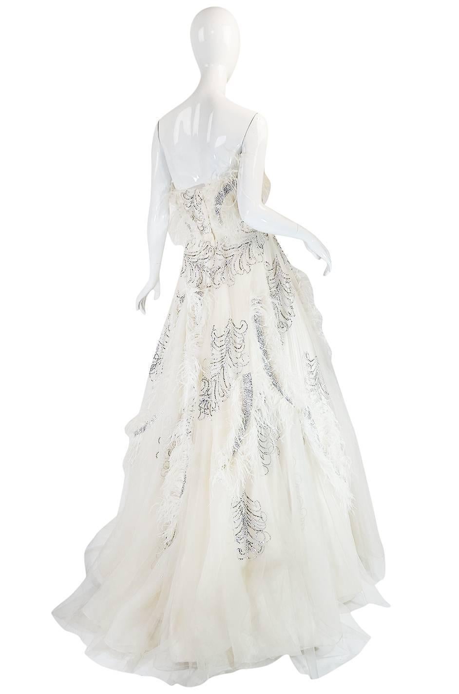 

This is an absolutely extraordinary vintage gown that is a once in a life time find. In person, the texture and depth created by the extravagant feathers and rhinestone applique, combined with the layers and layers of silk and net, is just