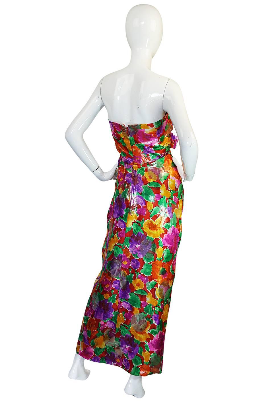 This beautiful Scaasi Boutique dress is made from a brilliantly colored metallic lame fabric that has a gorgeous abstract floral design strewn across its surface. The entire fabric has been given a metallic sheen and then there are gold circles