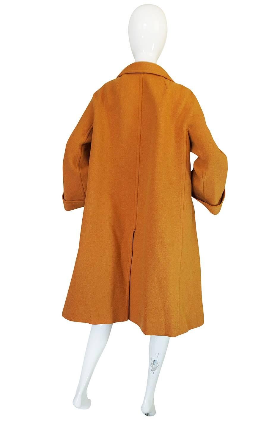 A fantastic swing coat by Pierre Balmain in a wonderful goldenrod color that is so flattering on. The coat is made of a lightweight wool that is very comfortable to wear but warm. The cut is a fabulous example of the loose, yet sculptural styles of