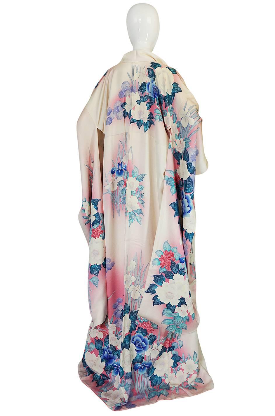 This stunning silk kimono has a dreamy and romantic print in shades of pinks and blues that range from the palest of colors to a deeply saturated pastel. It looks to have never been worn or used and would be perfect to use as wedding kimono or on