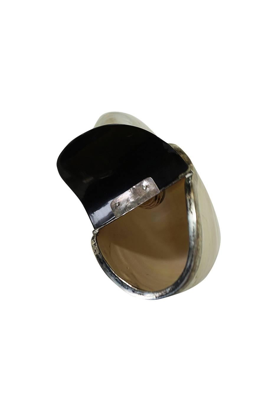 This is so unusual and beautiful and it is definitely not a bag you will see every day. A very large and beautiful sea shell has been glossed and coated to be made into a minaudiere. It has a combination of silver and a shaped black hinge opening